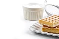 Belgium waffers with sugar powder on ceramic plate and strainer on white table