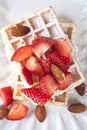 Belgium wafers with sugar powder, strawberries, almonds and chocolate on white ceramic plate Royalty Free Stock Photo