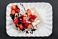 Belgium waffers with sugar powder, strawberries and chocolate on ceramic plate on black board background