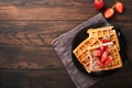 Belgium waffles. Homemade waffles with strawberries, powdered sugar and cup of coffee on black plate on old wooden table backgroun Royalty Free Stock Photo