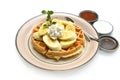 Belgium waffles with sliced banana and ice cream on a plate with chocolate toping and fruit sauce