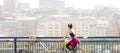 One young woman riding bike on city street bridge with blurry bright cityscape background