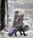 Two young women walking under umbrella in heavy snowfall in city street