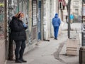 Young woman checking apps on her smartphone wearing a face mask in the streets of Belgrade in winter on coronavirus covid 19