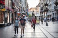 Young people, a couple, walking and holding hands in a Belgrade street wearing face mask