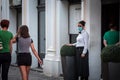 Waitress, a server in uniform, working at the terrace of a cafe waiting to serve clients wearing a respiratory face mask on Covid