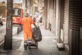 BELGRADE, SERBIA - JULY 19, 2022: Selective blur on a street cleaner, a roadsweeper, pulling a garbagebin while sweeping and