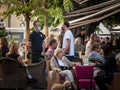 Waiter, a server working at the terrace of a cafe serving food to clients wearing a respiratory face mask on covid