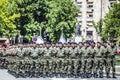 Rows of military troop marching on streets during sunny summer day