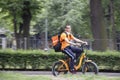 Young city delivery service courier riding an electric bike in city park