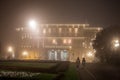 People walking in front of Stari Dvor, the City Hall of Belgrade, also called skupstina, at night, with a blurry fog of pollution Royalty Free Stock Photo