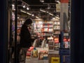 BELGRADE, SERBIA - SEPTEMBER 28, 2020: Female client, a girl, choosing a book in a bookstore wearing a respiratory face mask