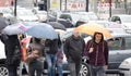 People under umbrellas crossing the street in rush hour with many cars in traffic jam on a rainy day