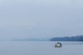 Belgrade under the fog seen from Zemun, with a boat in front, on the Danube river, and the fumes of an industrial chimney