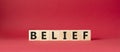 Belief symbol. Concept word Belief on wooden cubes. Beautiful red background. Business and Belief concept. Copy space