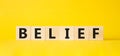 Belief symbol. Concept word Belief on wooden cubes. Beautiful yellow background. Business and Belief concept. Copy space