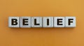 BELIEF - word on wooden cubes on a beautiful yellow background