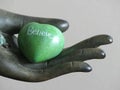 Green Heart Shaped Rock with the word BELIEVE etched in it held in a decorative hand statue