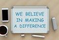 We Believe in Making a Difference, message on whiteboard, smart phone and coffee on table