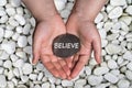 Believe word in stone on hand