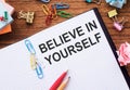 Believe in yourself - in notebook on a table with sticks colored paper clips and wrinkled sheets