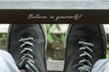 Believe in yourself. Self motivation. Self love and care inspirational words sign concept on wood and man feet with sneaker shoes