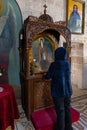 Believing woman stands and prays in front of the altar of the Monastery Deir Hijleh - Monastery of Gerasim of Jordan, in the