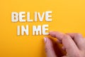Belive In Me. White wooden letters with text on a yellow background