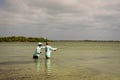 A Belizean fishing guide pointing out the school of bonefish to the fly fisherman