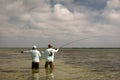 A Belizean fishing guide pointing out the school of bonefish to the fly fisherman