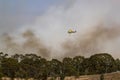 Bell 412 helicopter flying against plumes of smoke while fighting bush fires.