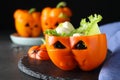 Bell pepper with black olives, mozzarella and lettuce as Halloween monster on dark table, closeup
