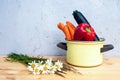 Bell pepper, carrots and corgette in rustic pot on wooden table with daisies Royalty Free Stock Photo