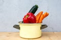 Bell pepper, courgette and carrots in rustic pot on wooden table Royalty Free Stock Photo