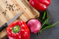Bell pepper, onion, chillies and knife on wooden board Royalty Free Stock Photo