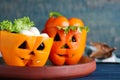 Bell peppers with black olives and lettuce as Halloween monsters on blue wooden table, closeup
