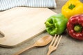 Bell peppers and kitchen utensils over wooden table. Royalty Free Stock Photo