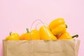 Bell peppers in paper bag on pink background flat lay. Zero waste shopping, plastic free. Shopping groceries online. Order fresh Royalty Free Stock Photo