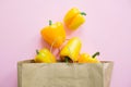 Bell peppers in paper bag on pink background flat lay. Zero waste shopping, plastic free. Shopping groceries online. Order fresh Royalty Free Stock Photo