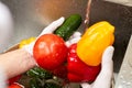 Bell peppers, tomatoes and cucumber are washing under running.