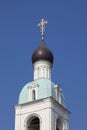 The bell tower of an ancient Orthodox church with a gilded cross against a clear sky Royalty Free Stock Photo