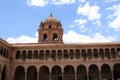 The bell tower atop a two story stone building lined with columns and arches in Cusco, Peru, South America