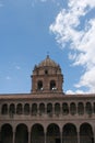 A bell tower atop a two story stone wall lined with columns and arches at the Belmond Monasterio Hotel in Cusco, Peru