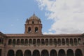 A bell tower atop a two-story stone wall lined with columns and arches and filled with flowers at the Belmond Monasterio Hotel