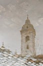 Bell tower of the Basilica of Our Lady of Pillar reflected in a puddle of water