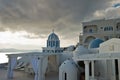 Bell tower and blue dome of a church under dramatic sky at sunset, Imerovigli village, Santorini island Royalty Free Stock Photo