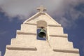Bell tower with cross in Mykonos, Greece. Chapel building detail architecture. White church on cloudy blue sky. Religion Royalty Free Stock Photo