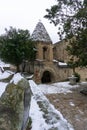 Bell tower of monastery in snowy weather. Tiled roof covered by snow, cross on top. Gate leading to the basement. Shiomgvime Royalty Free Stock Photo