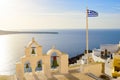 Bell tower and national flag of Greece in sunset light in Oia, Santorini, Greece Royalty Free Stock Photo