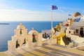 Bell tower and national flag of Greece in sunset light in Oia, Santorini, Greece Royalty Free Stock Photo